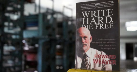 A copy of Howard Weaver’s memoir “Write Hard, Die Free” rests on an ink-splotched guard rail in front of the Peninsula Clarion’s defunct Goss Suburban printing press in Kenai, Alaska, on Thursday, June 20, 2024. (Jake Dye/Peninsula Clarion)