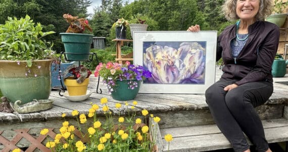 Jan Peyton poses with "Open Heart," a watercolor painting she began in 2003 and recently completed, on Wednesday, June 26, 2024, at her home in Homer, Alaska. "Open Heart" will be on display in her solo exhibit, "Ode to Fireweed," in July at Fireweed Gallery. Photo by Christing Whiting