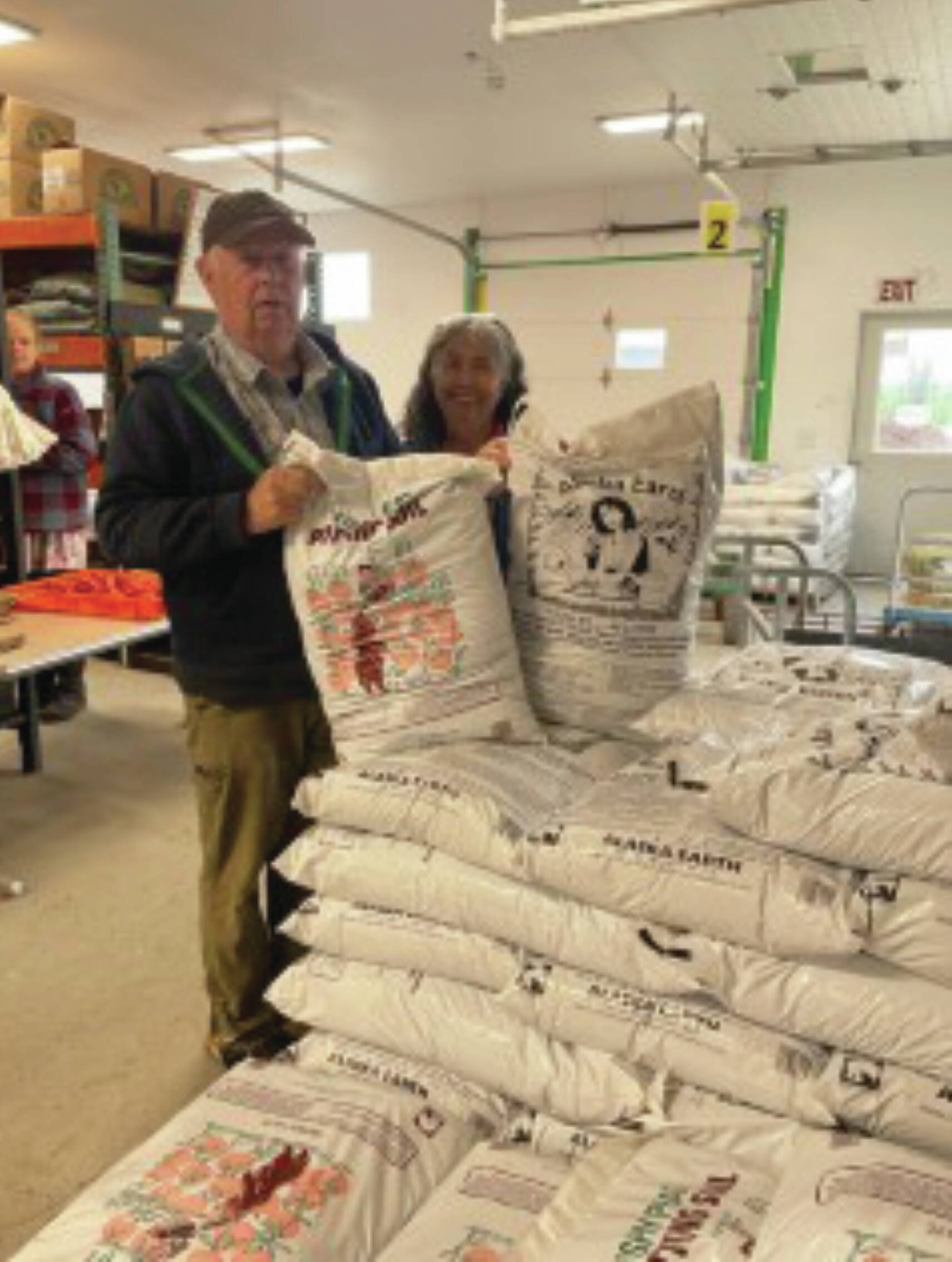 Al and Grace Poindexter pose with the Fishy Peat potting soil in the Anchor Point Greenhouse on July 8, 2024. (Emilie Springer/ Homer News)