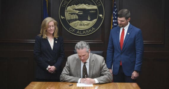 Gov. Mike Dunleavy signs Senate Bill 179, while Sen. Jesse Bjorkman, right, stands by on Aug. 13, 2024. (Photo provided by Sen. Jesse Bjorkman)