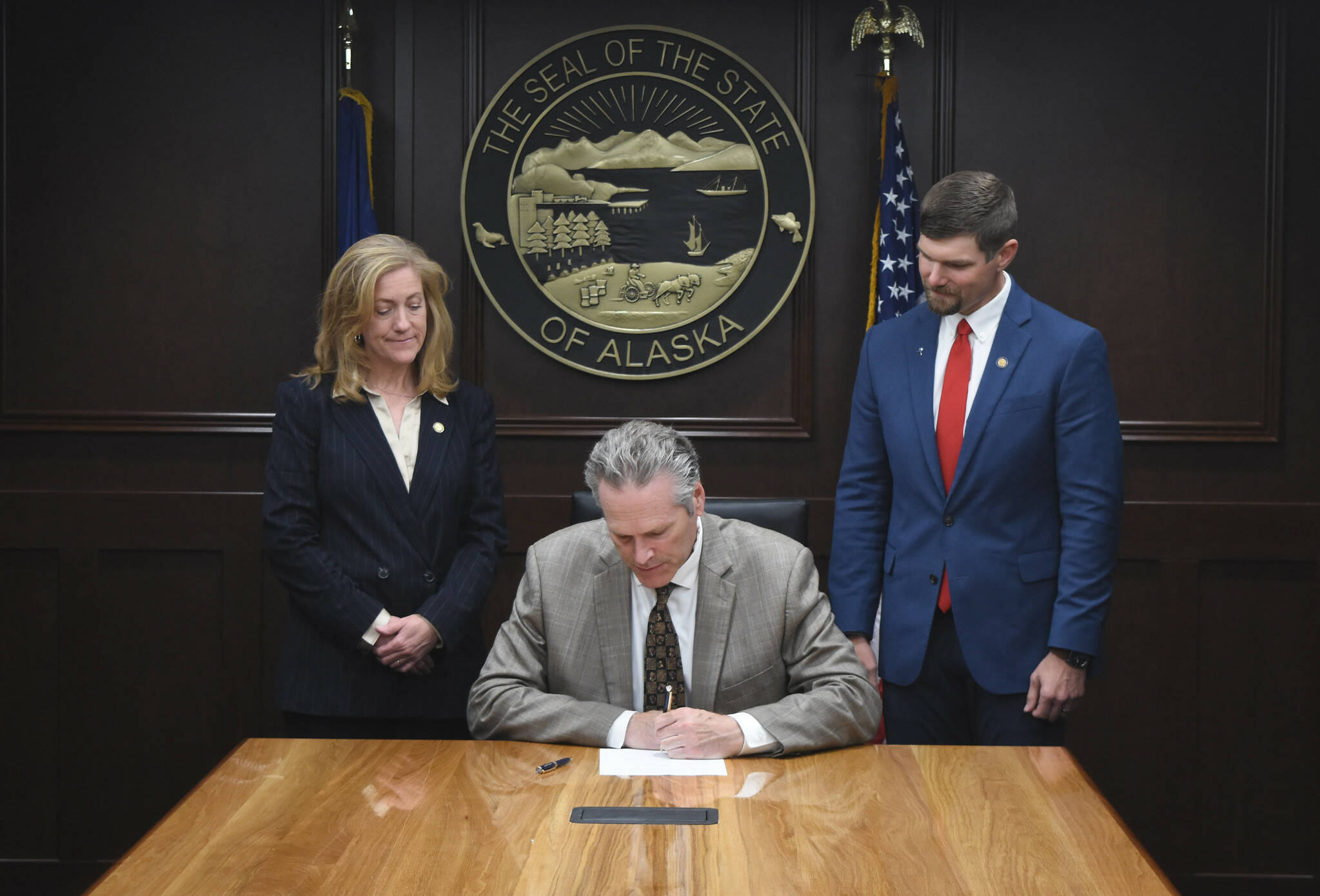 Gov. Mike Dunleavy signs Senate Bill 179, while Sen. Jesse Bjorkman, right, stands by on Aug. 13, 2024. (Photo provided by Sen. Jesse Bjorkman)