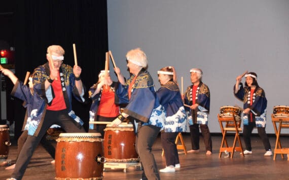 Frank Jeffries (front left) and Jacki Holzman (front right) play together during Tomodachi Daiko’s first taiko drum performance on Saturday, May 4, 2024 in the Homer High School Mariner Theatre in Homer, Alaska. Pictured in the background are Naoyuki Furuta (left), one of the leaders of Tokyo-based taiko group Chokoma, and TDI founder Sachiko Kono (right). (Delcenia Cosman/Homer News)