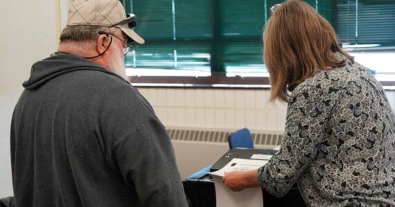 A poll worker helps a voter cast their ballot at the Soldotna Regional Sports Complex in Soldotna, Alaska, during the Alaska Primary Election on Tuesday, Aug. 20, 2024. (Jake Dye/Peninsula Clarion)