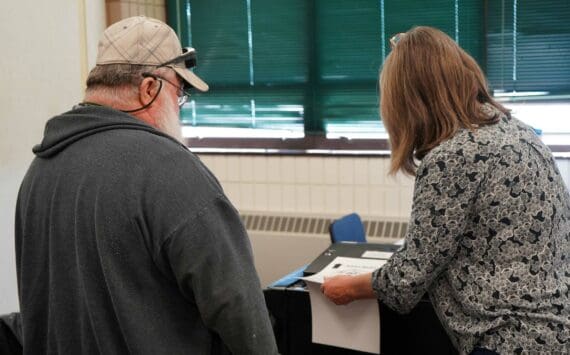 A poll worker helps a voter cast their ballot at the Soldotna Regional Sports Complex in Soldotna, Alaska, during the Alaska Primary Election on Tuesday, Aug. 20, 2024. (Jake Dye/Peninsula Clarion)