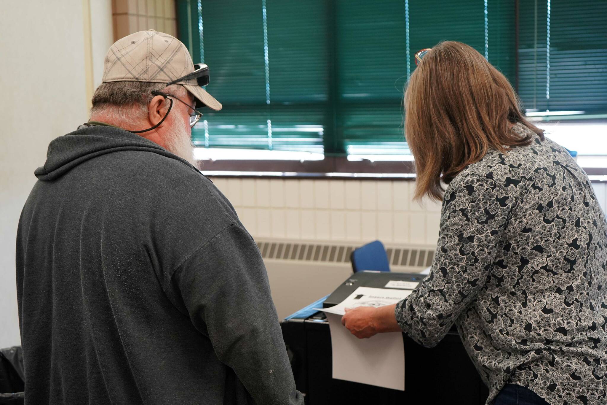 A poll worker helps a voter cast their ballot at the Soldotna Regional Sports Complex in Soldotna, Alaska, during the Alaska Primary Election on Tuesday, Aug. 20, 2024. (Jake Dye/Peninsula Clarion)