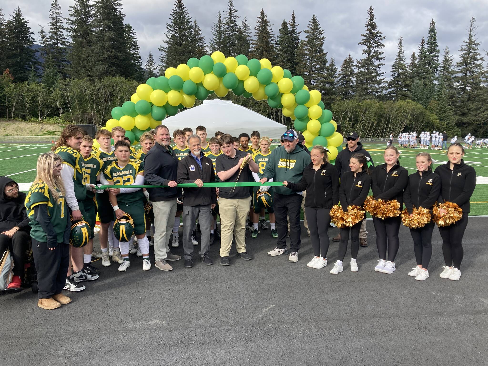 Center, from left: Kenai Peninsula Borough School District Superintendent Clayton Holland; Borough Mayor Peter Micciche; Seward High School Student Council President Otto Nipp; and Seward High School Principal Dr. Henry Burns participate in a ribbon-cutting ceremony for a new turf field at Roger Steinbrecher Memorial Field at Seward High School, Friday, Sept. 13, 2024, in Seward, Alaska. (Photo by Jeff Helminiak/Peninsula Clarion)