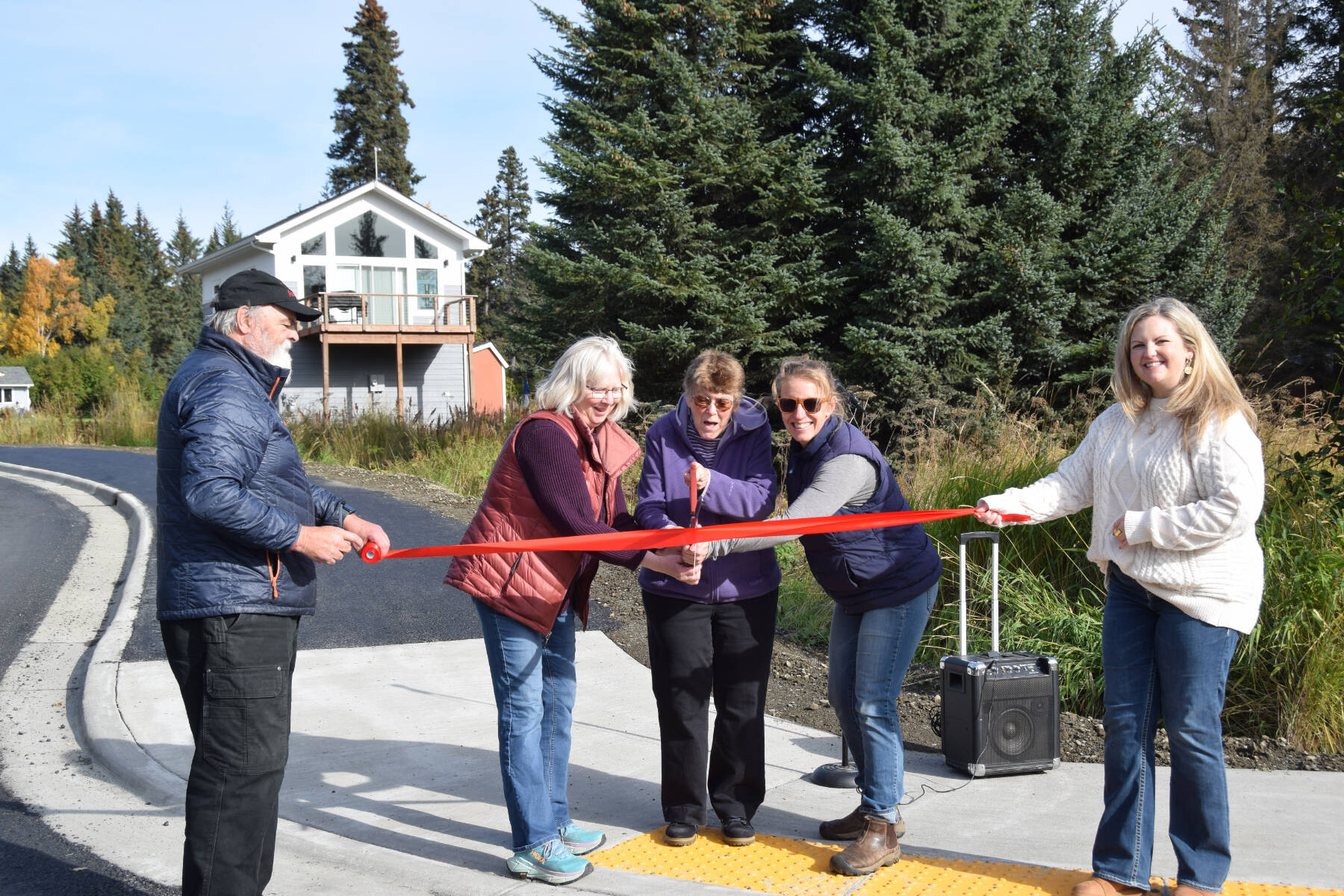 (from left to right) Homer mayor Ken Castner, city council members Shelly Erickson, Caroline Venuti and Rachel Lord, and city manager’s assistant Lori Pond conduct a ribbon cutting ceremony for the newly completed Ben Walters Lane Sidewalk Project on Monday, Sept. 30, 2024, at the corner of Ben Walters Lane and Smoky Bay Way in Homer, Alaska. (Delcenia Cosman/Homer News)