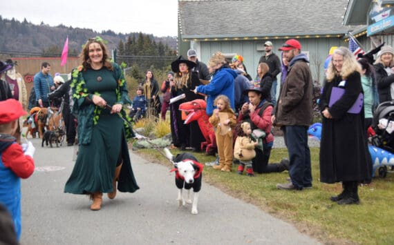 Sleeping Sisters AK artist Joanne Glaves and her dog, Newt, stride past the judges and cheering audience during the Pet Costume Contest at the Fall Fest at the Homer Chamber of Commerce on Saturday, Oct. 28, 2023 in Homer, Alaska. (Delcenia Cosman/Homer News)