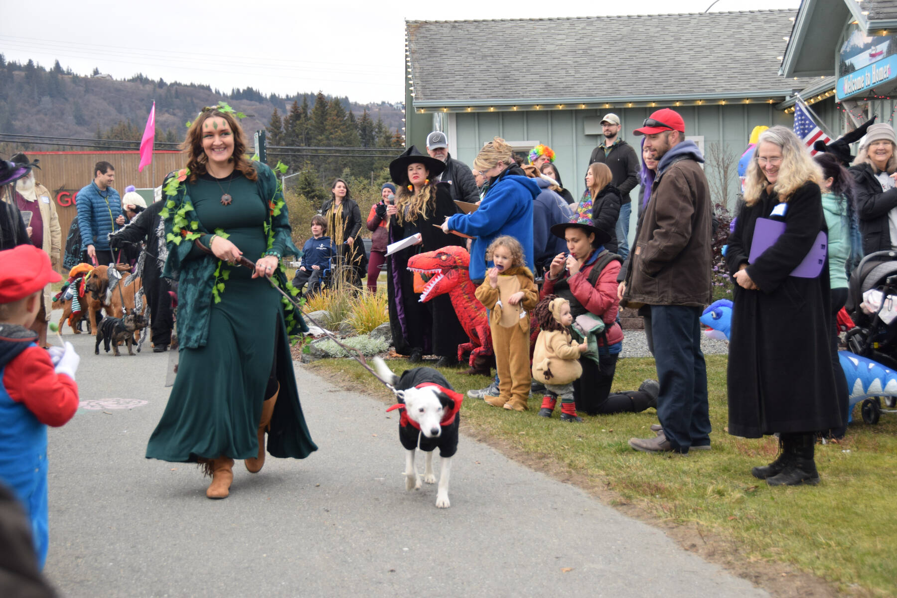 Sleeping Sisters AK artist Joanne Glaves and her dog, Newt, stride past the judges and cheering audience during the Pet Costume Contest at the Fall Fest at the Homer Chamber of Commerce on Saturday, Oct. 28, 2023 in Homer, Alaska. (Delcenia Cosman/Homer News)