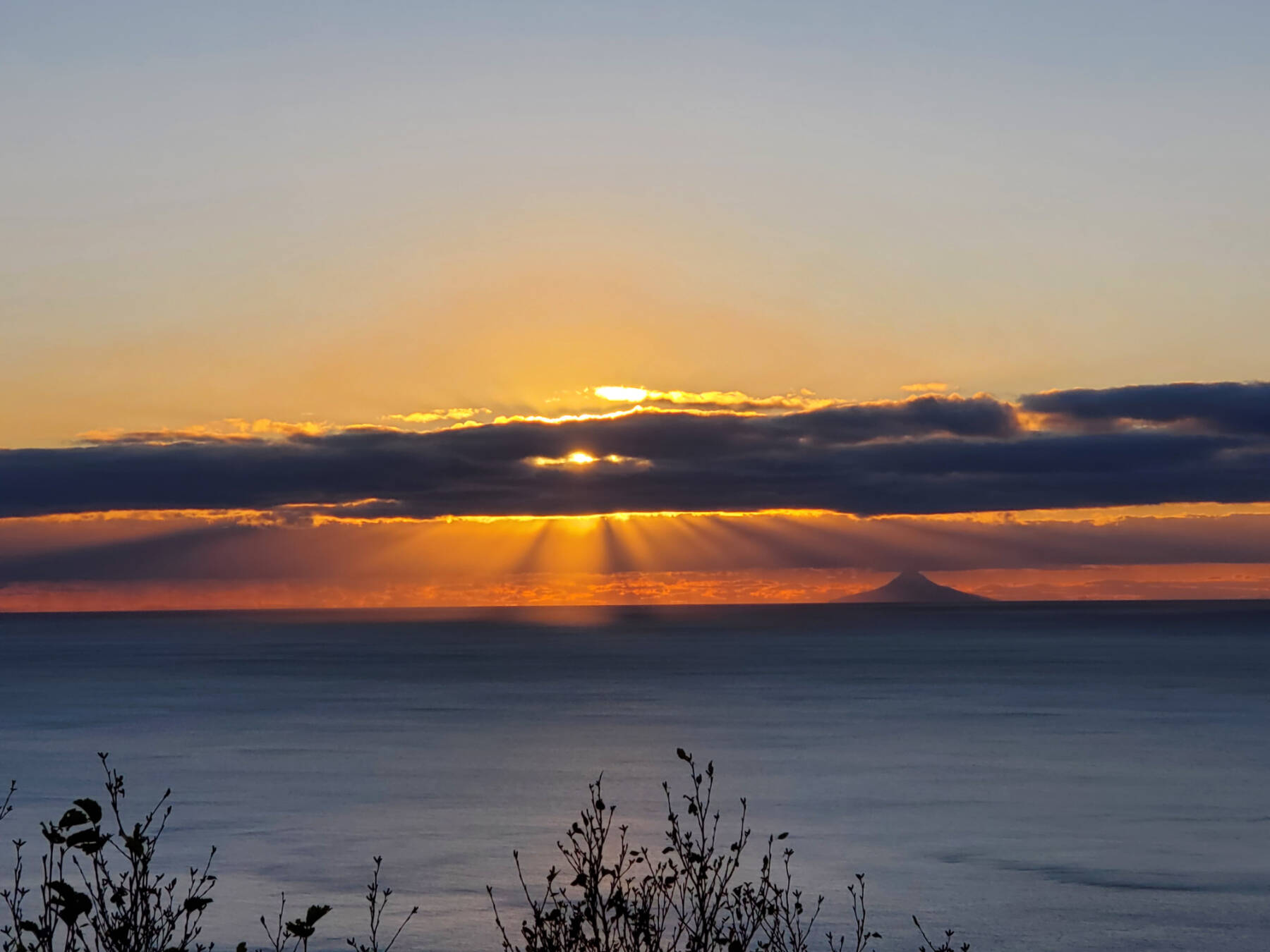 The setting sun over Kachemak Bay highlights Mt. Augustine in the distance on Thursday, Oct. 17, 2024, in Homer, Alaska. (Delcenia Cosman/Homer News)