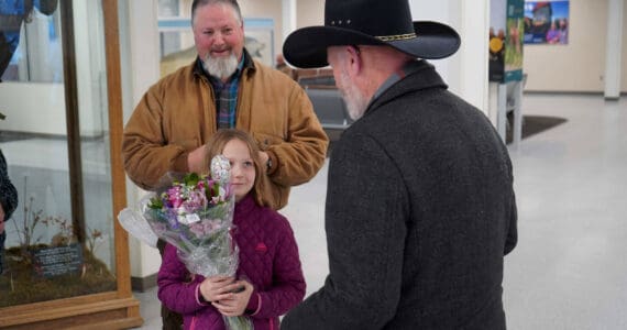 Rose Burke, center left, is celebrated for winning the U.S. Capitol Christmas Tree essay contest by Connections Homeschool Principal Douglas Hayman, right, at the Kenai Municipal Airport in Kenai, Alaska, on Friday, Nov. 1, 2024. (Jake Dye/Peninsula Clarion)