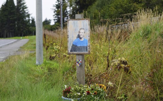 A memorial for Drew Brown with his photo, flowers and a heart sculpture was installed at the site where he died in a car crash on the Sterling Highway, as seen here on Friday, Sept. 16, 2022, in Homer, Alaska. (Photo by Michael Armstrong/Homer News)