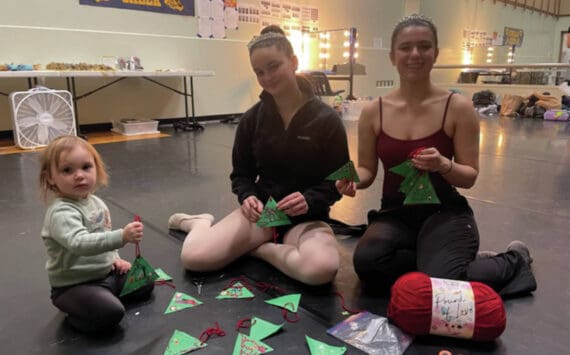 Homer “Nutcracker” dancers Ella Gustufson and Sofia Loboy help create Christmas tree gift tags for the 2024 Homer Share the Spirit in the Homer High School green room during “Nutcracker” rehearsal last weekend. They are joined by one of the Nutcracker’s small participants. (Emilie Springer/Homer News)