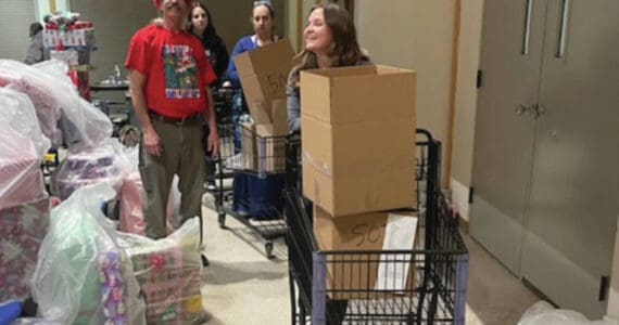 Rick Cline loads up a cart for his daughter Aiyana to bring to the delivery dock at the Share the Spirit preparation event at Homer High School on Saturday,. (Emilie Springer/ Homer News)