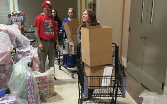 Rick Cline loads up a cart for his daughter Aiyana to bring to the delivery dock at the Share the Spirit preparation event at Homer High School on Saturday,. (Emilie Springer/ Homer News)