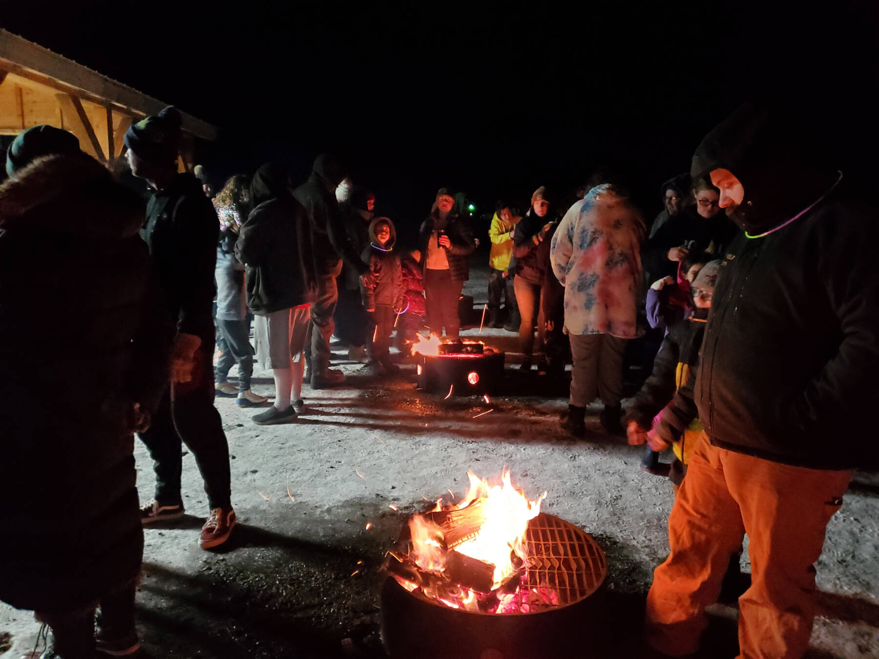 Community members gather around fire pits at the pavilion next door to Great Land Worship Center in Anchor Point, Alaska, to await the New Year’s Eve fireworks show conducted by the Virl “Pa” Haga VFW Post 10221 on Dec. 31, 2024. (Delcenia Cosman/Homer News)