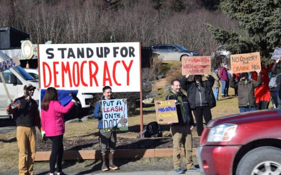 Community members hold up protest signs during the Stand for Democracy Rally on International Women’s Day, March 8, 2025, at WKFL Park in Homer, Alaska. (Chloe Pleznac/Homer News)